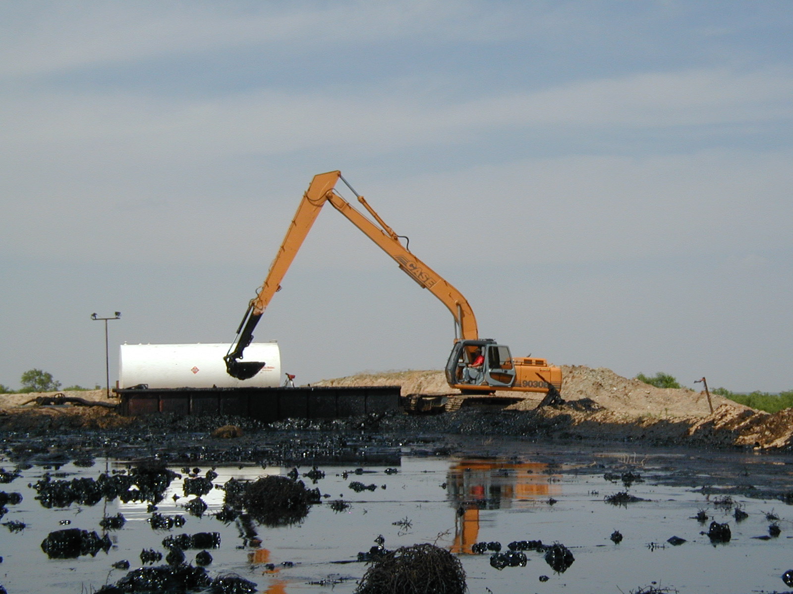 Excavator cleaning an oil-sludge lake at the Westex project